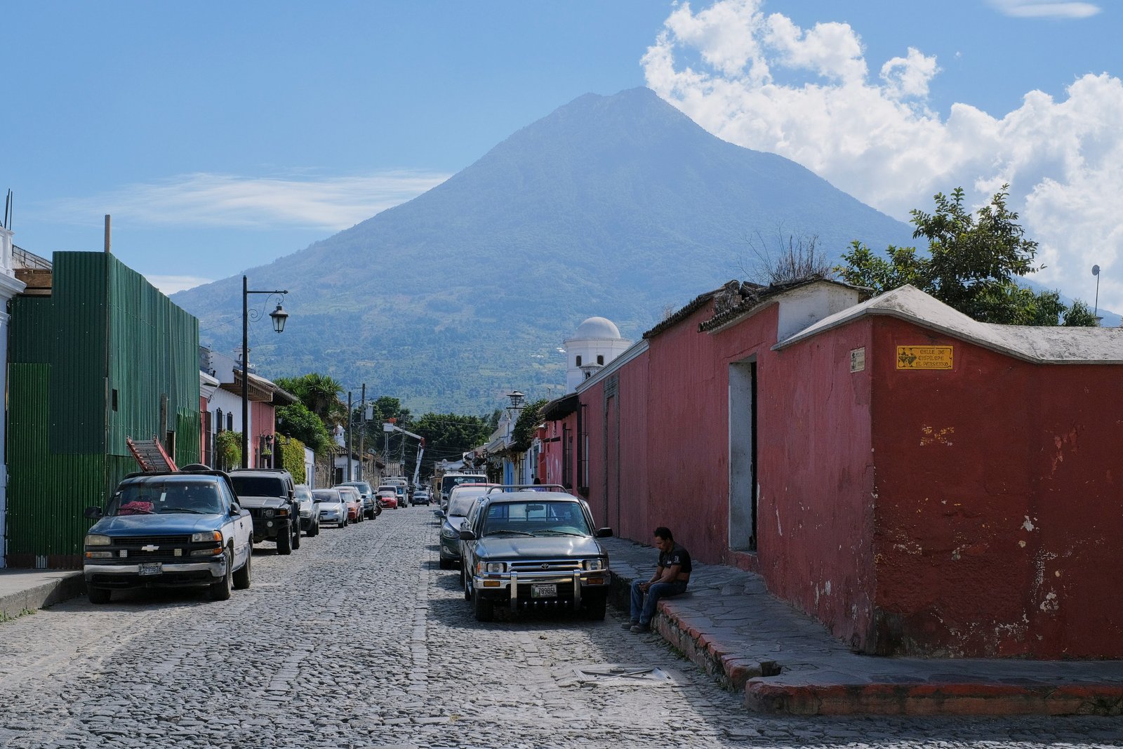 Cobblestone street of Antigua Guatemala with colonial facades and Volcan Agua rising above the city at the end of the road