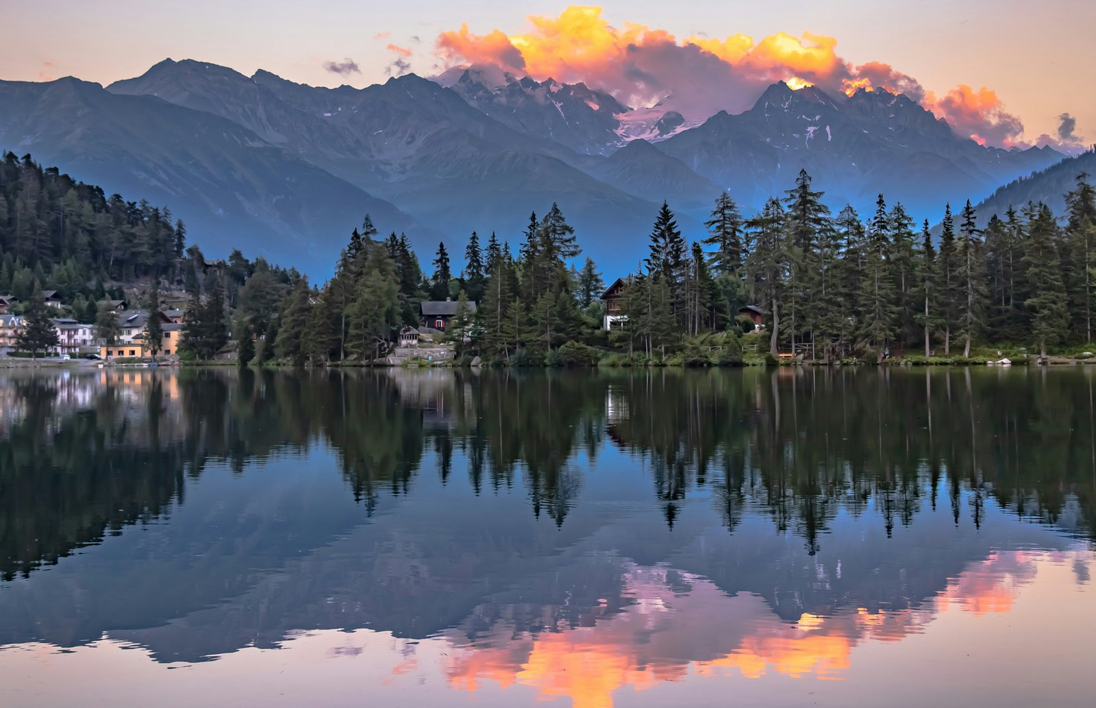Green forest and mountain rising above a glacial lake in the Pyrenees