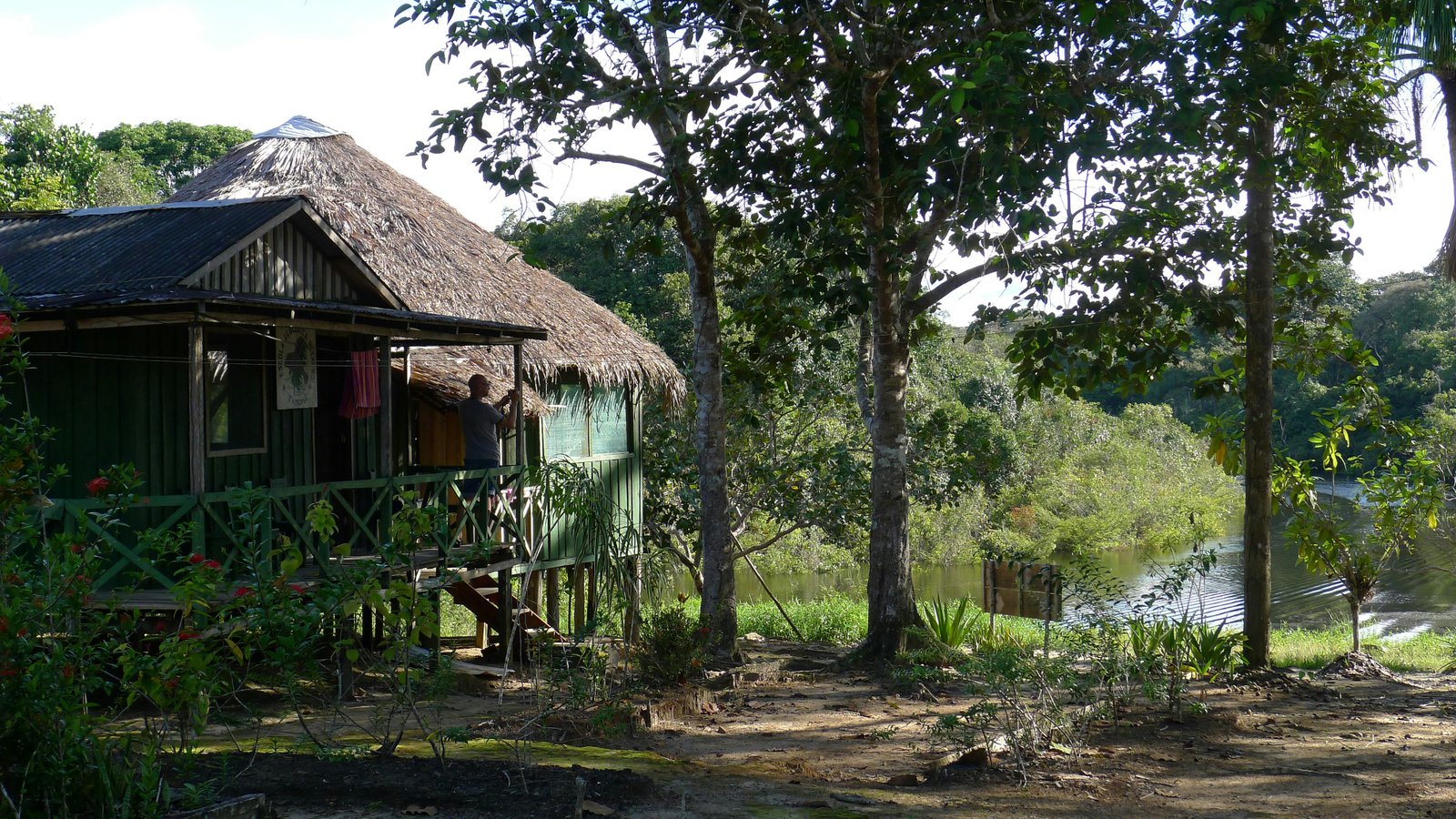 River lodge on the Amazon. Stilted structure at the waterline, jungle behind.
