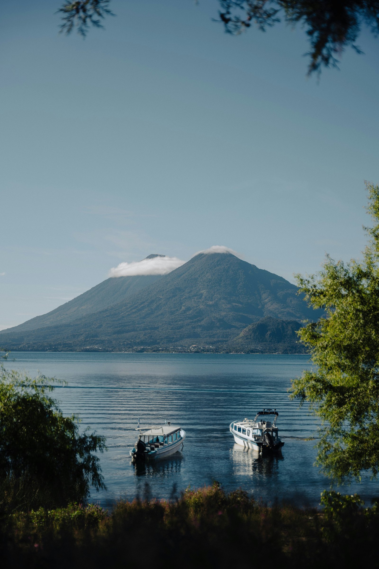 Sunset over Lago de Atitlan with volcano silhouettes and wooden boats