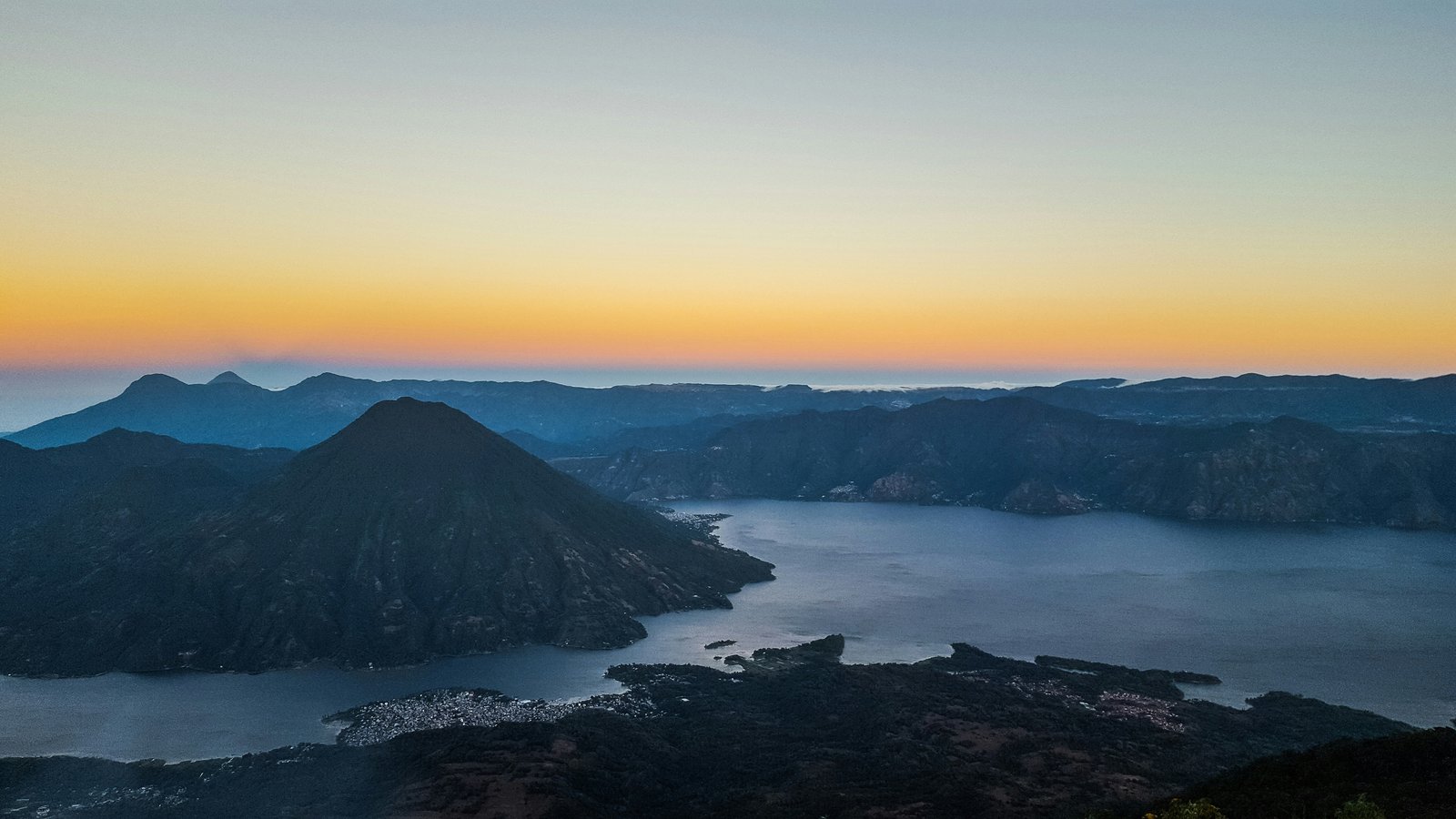 Lake Atitlan from above at sunset, volcanoes and lakeside villages visible from the highlands