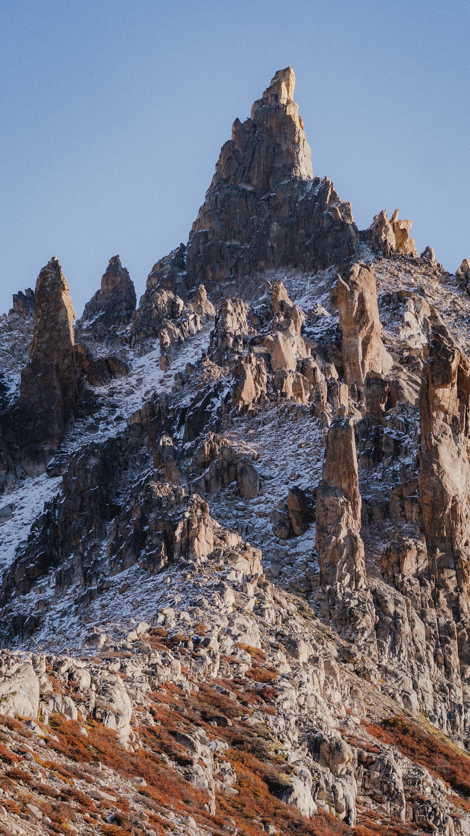 Twin pinnacles against a clear blue sky. Autumn forest on the lower slopes.