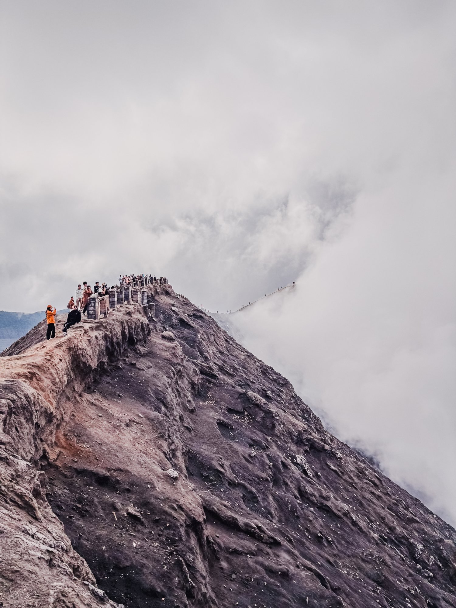 The rim of the crater with the cloud pouring over it. A few people sitting at the edge.