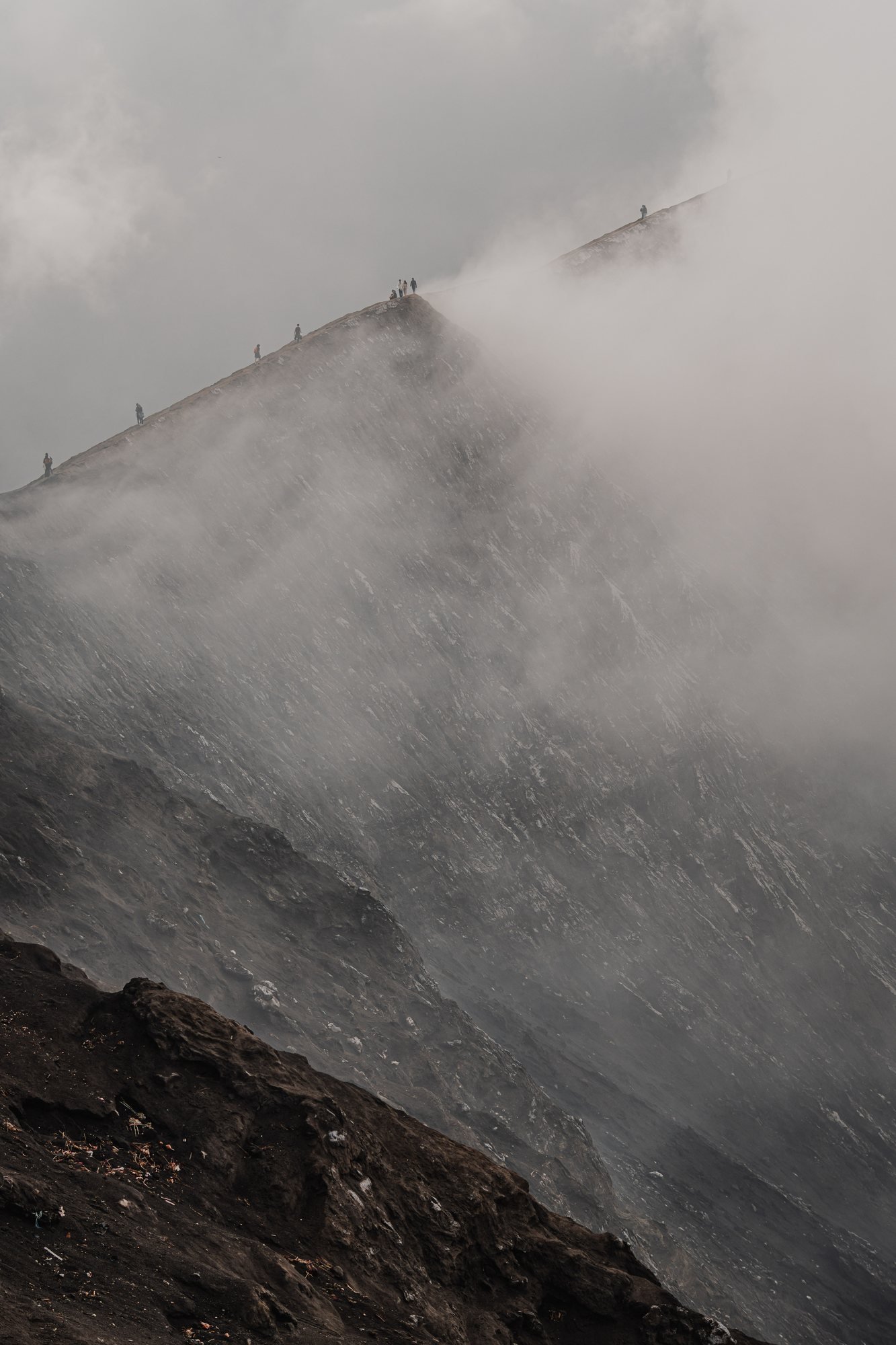 Hikers on the rim, almost lost in the steam. The wind shifts and the whole view disappears.
