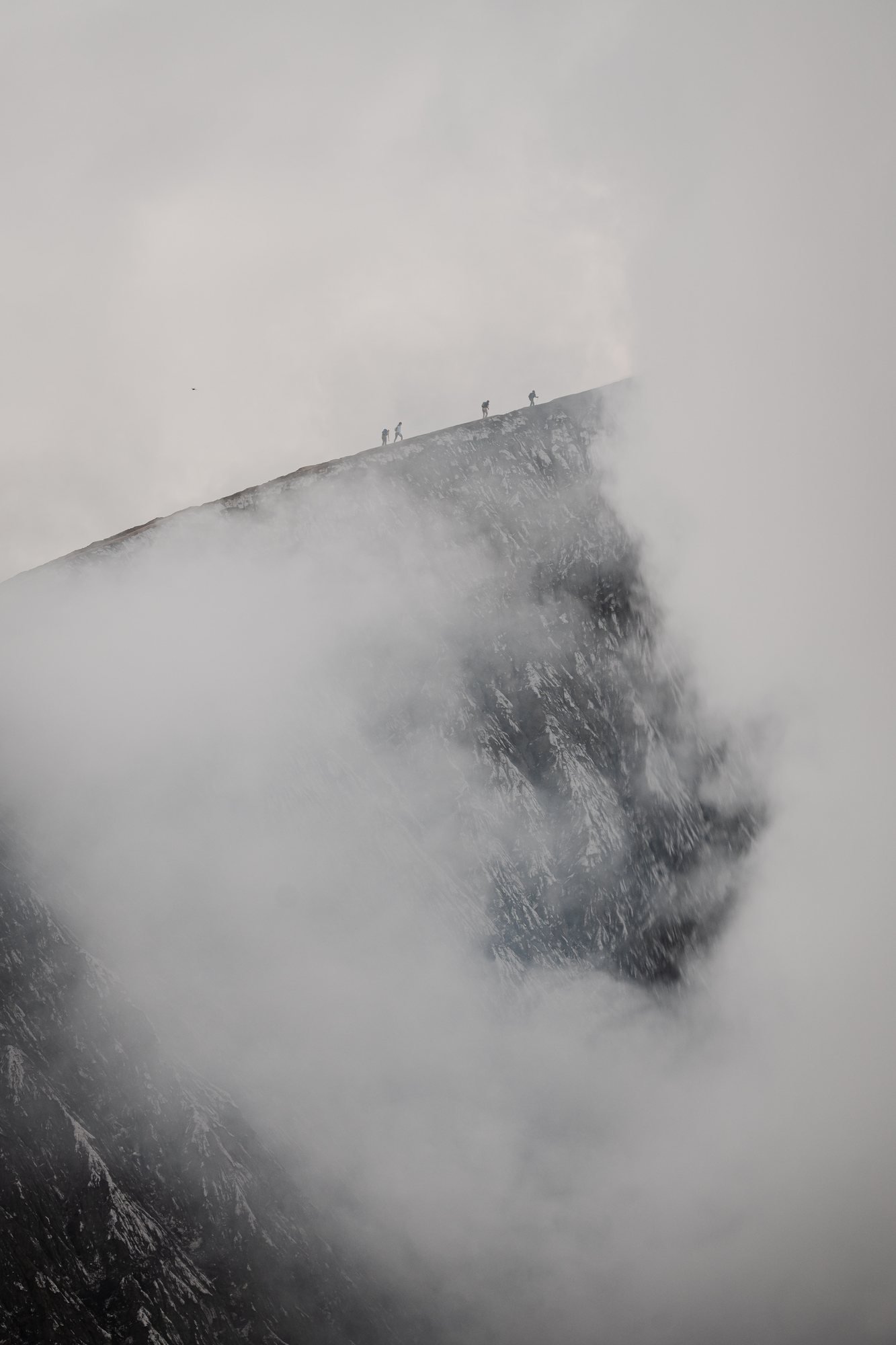 A group walking the edge of the crater. The steam comes and goes in seconds.
