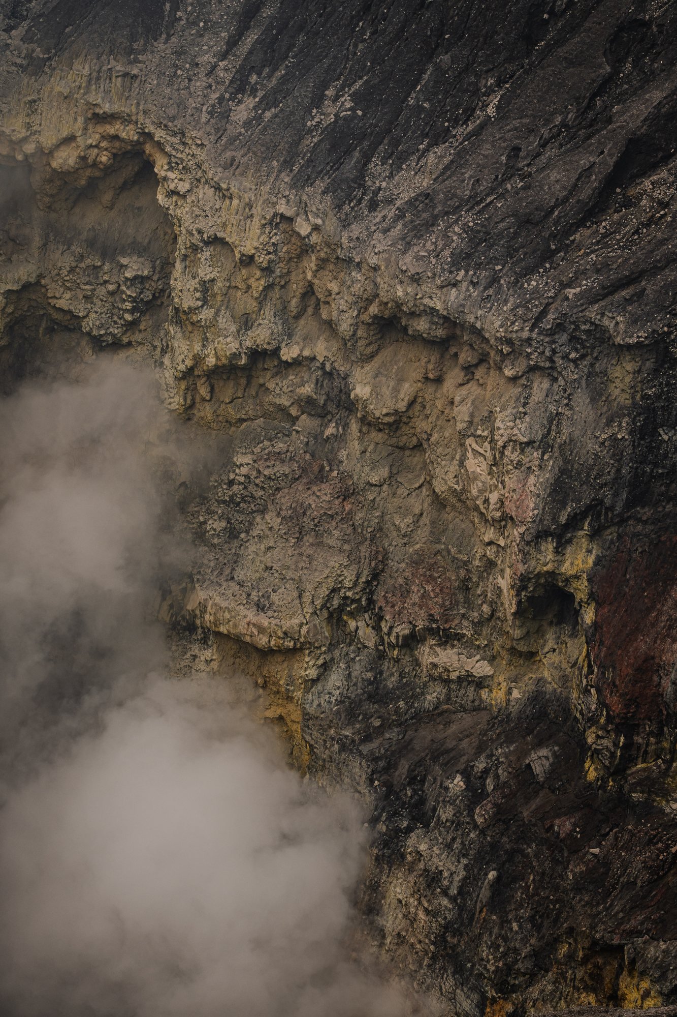 The inner wall streaked with sulfur yellow. Steam gathers at the base of the frame.