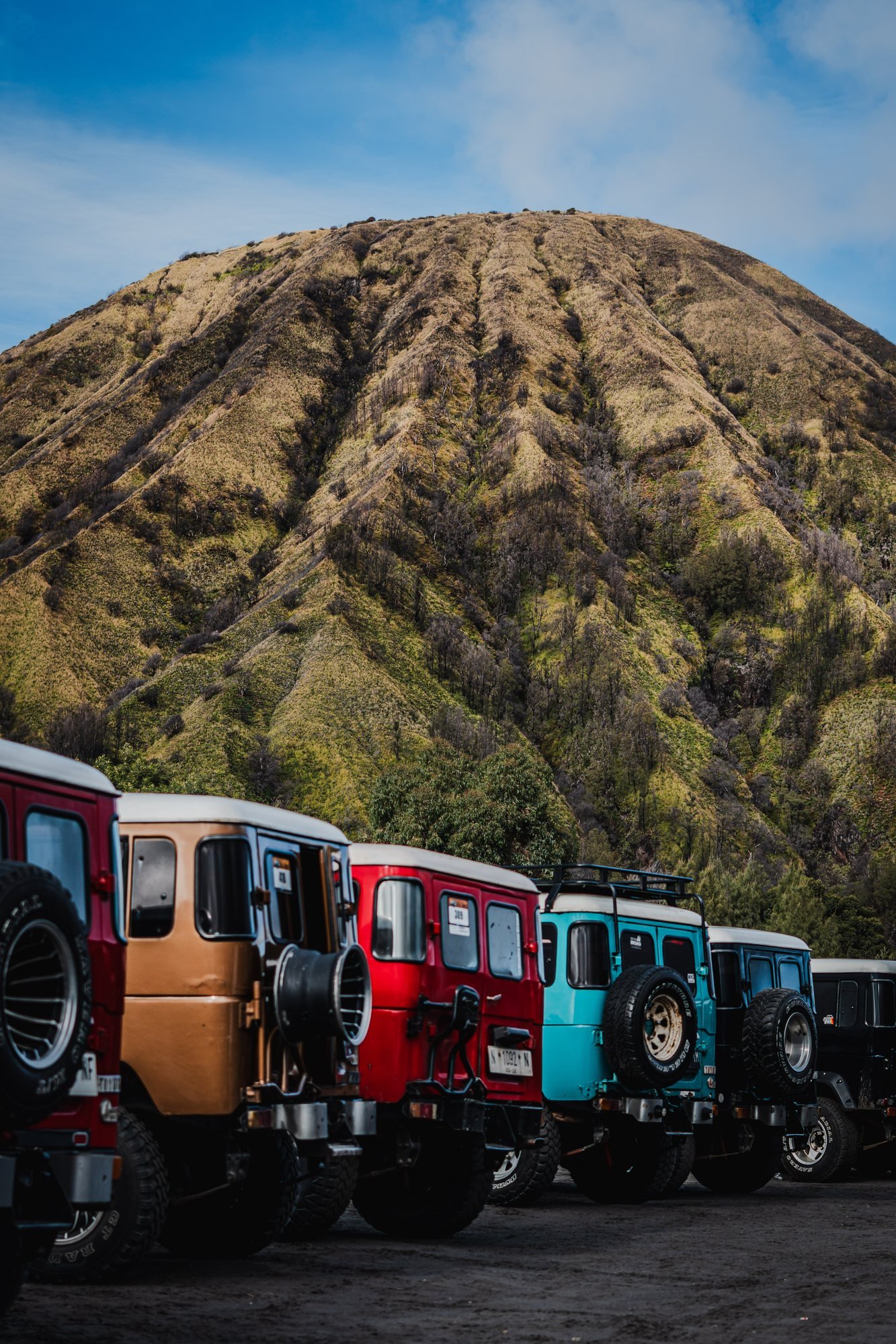 Jeeps lined up at the foot of Batok, each one painted a different color.