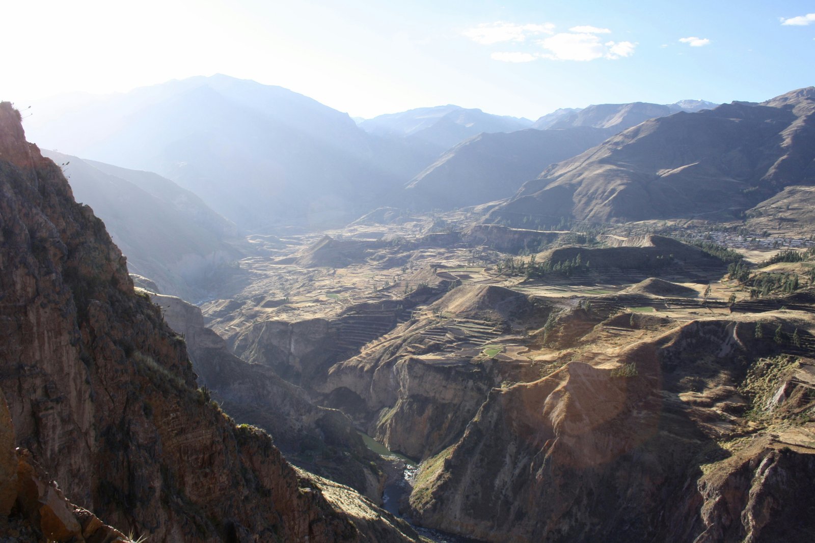 Colca Canyon at sunrise with the river gorge far below and Inca terraces on the opposite wall