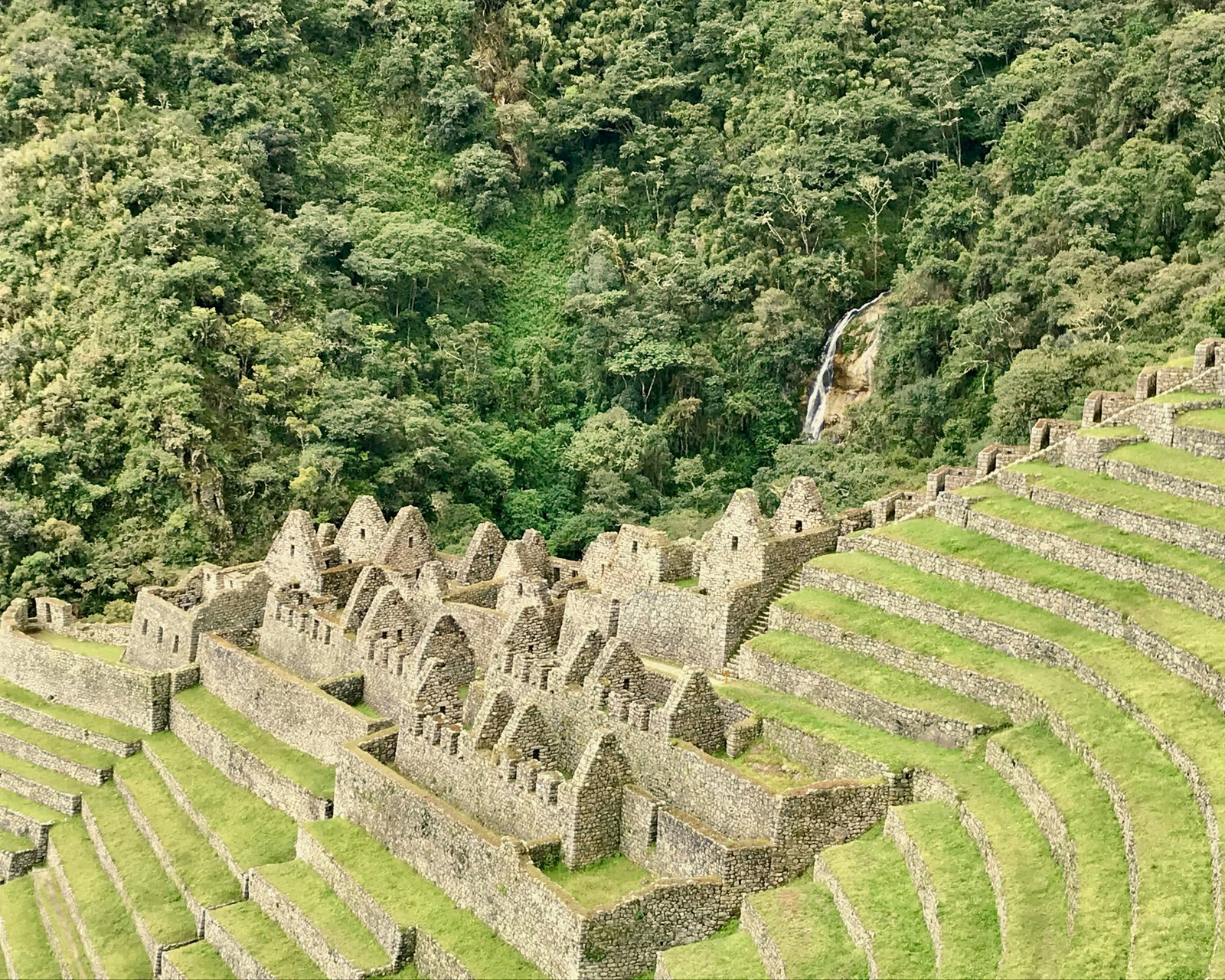 Winawayna terraced ruins and stone buildings above the Urubamba gorge with a waterfall behind