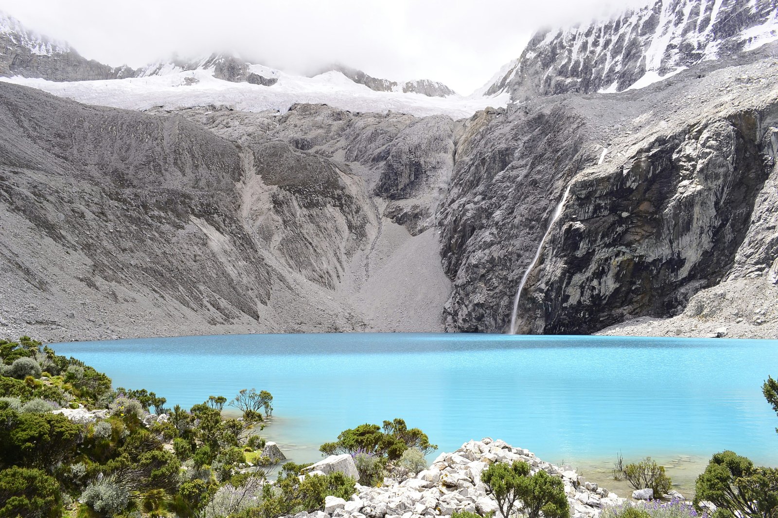 Laguna 69 from the shore with glacial waterfall dropping into the turquoise water