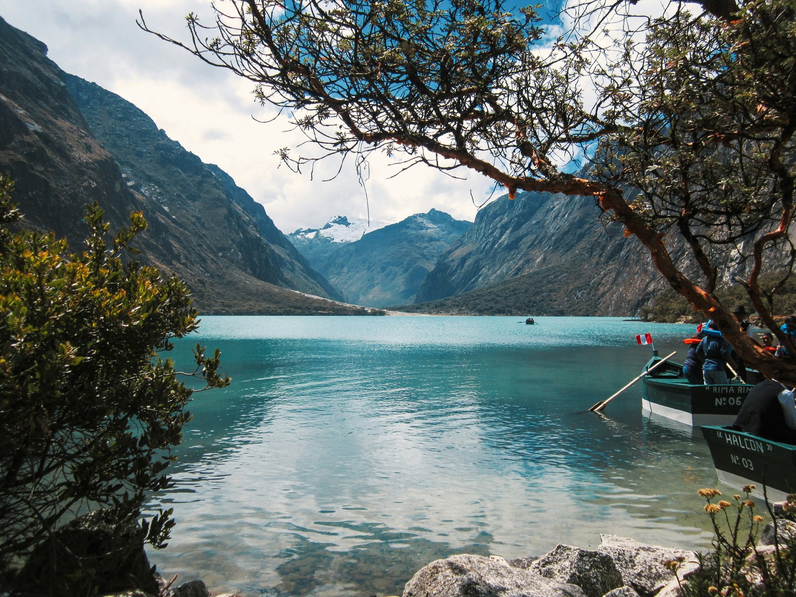 Rowboat on turquoise glacial lake below a massive snow-covered Andean peak