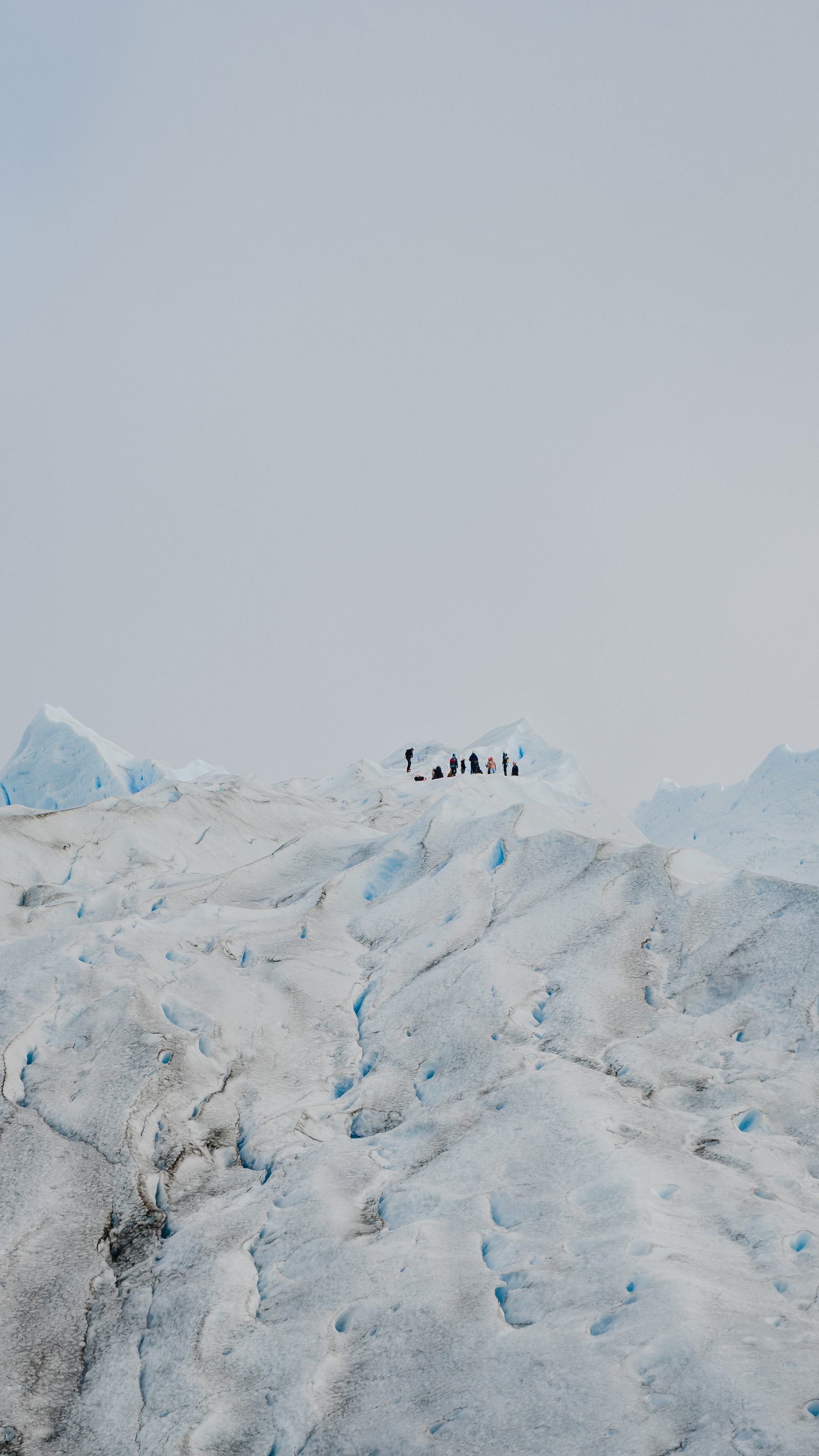 Two trekkers in the meltwater channels. The glacier goes all the way to the horizon behind them.
