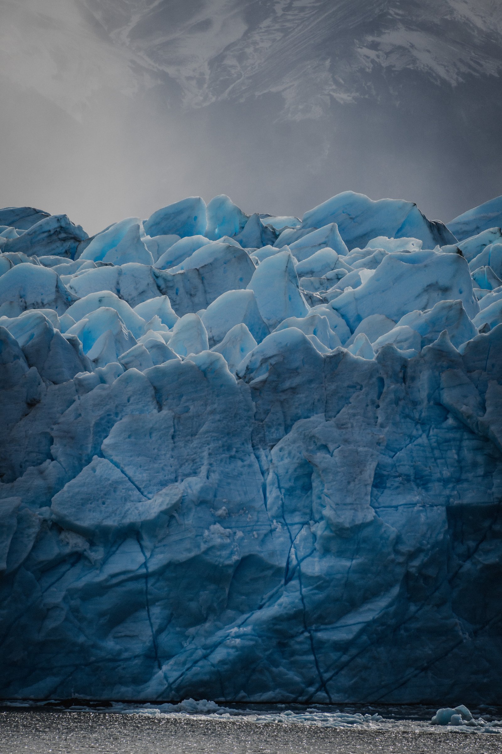 Fractured blue ice at the glacier's face. Stormy sky above.