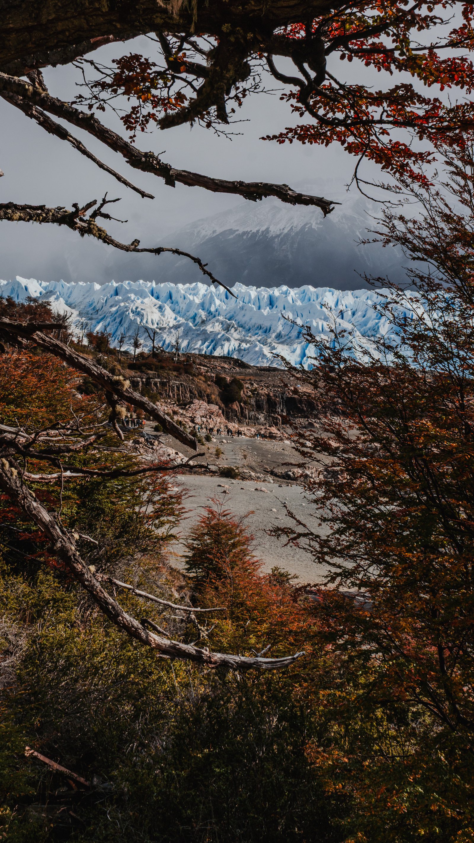 Moraine valley below. Trekkers visible as distant dots.