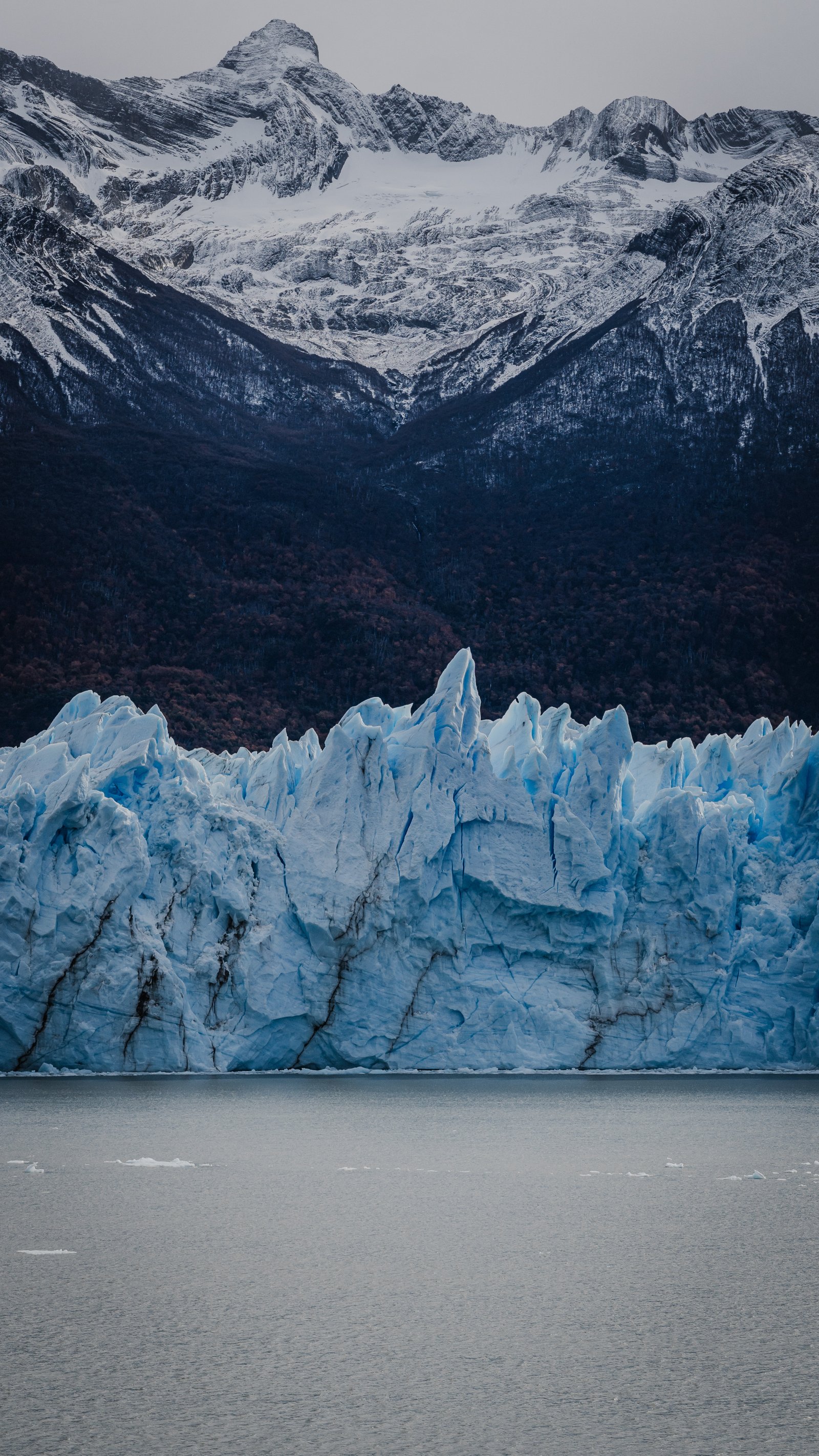 Isolated ice spire against dark autumn forest.
