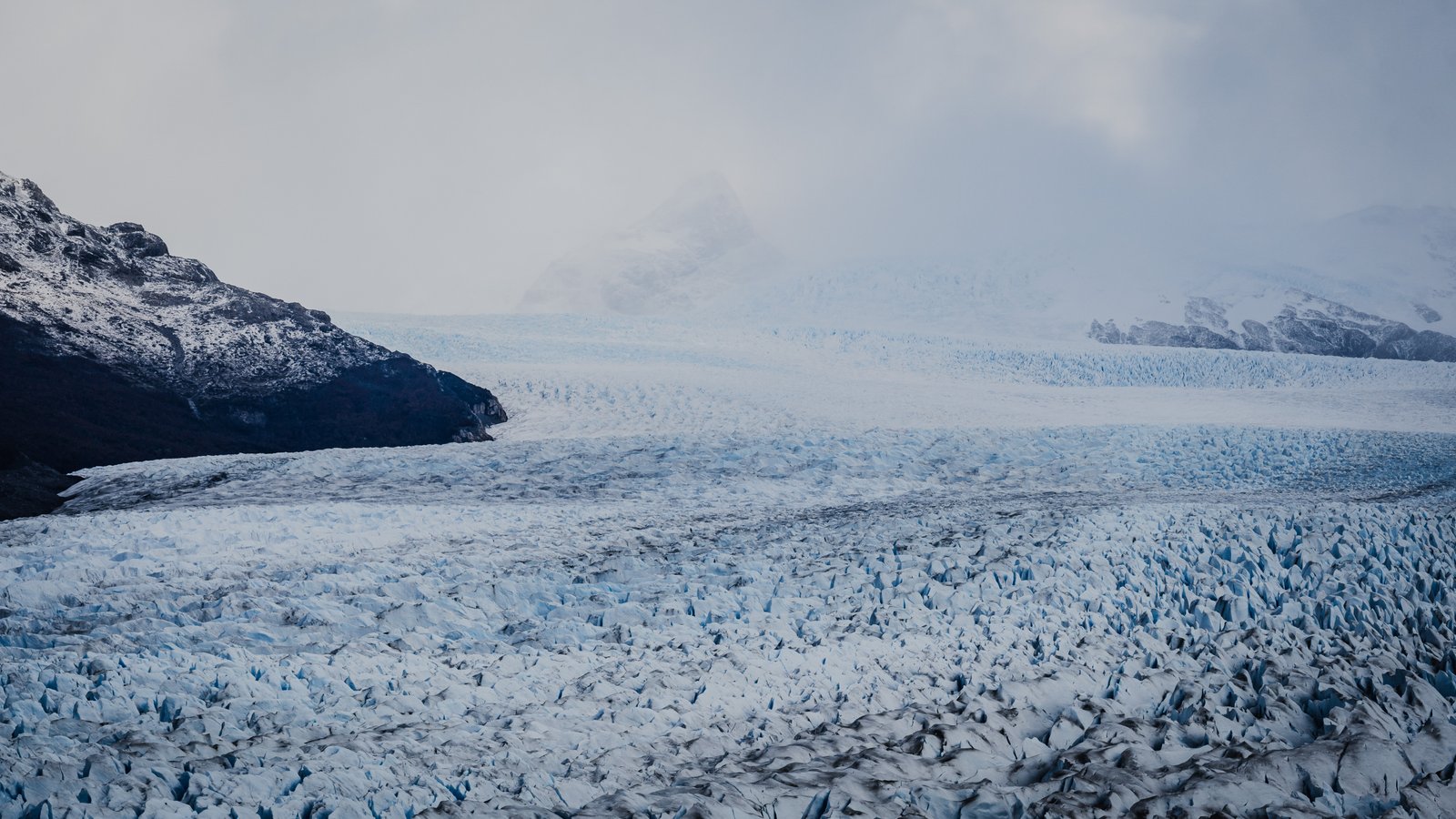 The glacier edge against the dark mountain. The boundary between ice and rock.